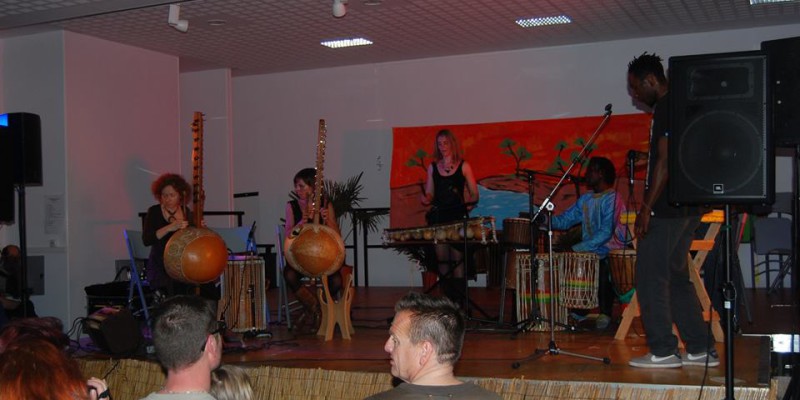 Concert de musique traditionnelle avec des instruments africains, dans une salle pleine de spectateurs.