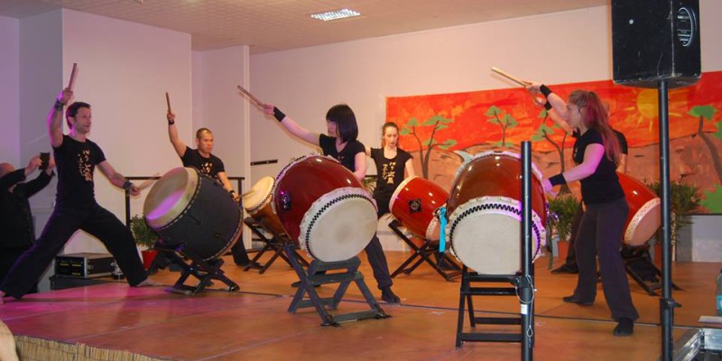 Groupe de percussionnistes jouant du taiko sur scène, dans une ambiance festive à Feuguerolles-Bully.