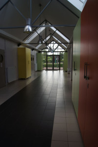 Intérieur d'un bâtiment communal à Feuguerolles-Bully, avec des placards colorés et des fenêtres donnant sur un jardin.