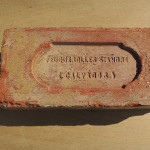 Brique en terre cuite estampillée "Feuguerolles Standard" posée sur une surface en bois.