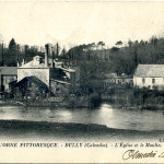 Vue sur le moulin et l'église à Bully, commune de Feuguerolles-Bully, dans le Calvados.