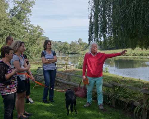 Visite guidée au bord d'un étang à Feuguerolles-Bully, avec un groupe observant un animateur au sol.