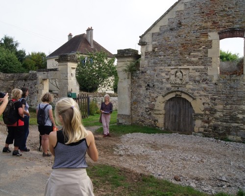 Groupe de visiteurs devant une ancienne bâtisse à Feuguerolles-Bully, avec une guide présentant le site.