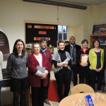 Groupe de personnes dans une médiathèque, affichant des livres et des publications.