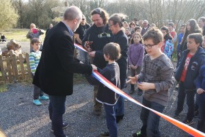 Inauguration d'un événement local avec des enfants et des adultes, incluant une coupe de ruban.