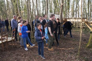 Groupe d'enfants et d'adultes présents dans une forêt, observant une activité en plein air à Feuguerolles-Bully.
