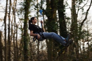 Jeune en train de faire de la tyrolienne dans une forêt à Feuguerolles-Bully.