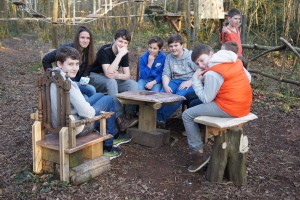 Groupe d'enfants assis autour d'une table en bois, dans une forêt, près de Feuguerolles-Bully.