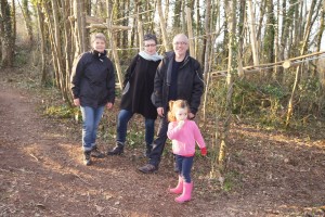 Quatre personnes et une enfant se tiennent sur un chemin forestier, entourées d'arbres dans une ambiance naturelle.