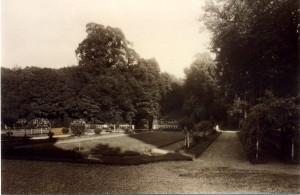 Vue d'un jardin verdoyant, bordé d'arbres, avec des allées et des parterres de fleurs à Feuguerolles-Bully.