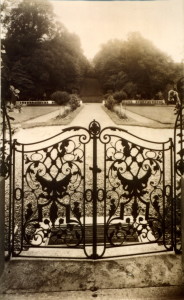 Vue d'un portail en fer forgé s'ouvrant sur un chemin entouré de jardins verdoyants à Feuguerolles-Bully.