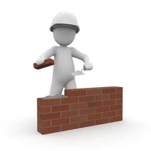 Ouvrier en construction posant des briques pour ériger un mur.