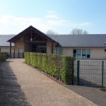 École de Feuguerolles-Bully, avec allée et haies, vue sur la cour extérieure.