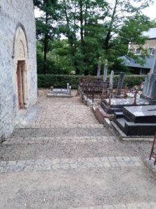 Vue des escaliers menant à un cimetière ancien, avec tombes et cryptes, à proximité d'une église à Feuguerolles-Bully.