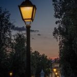 lampadaire éclairant un chemin bordé d'arbres à la tombée de la nuit à Feuguerolles-Bully.