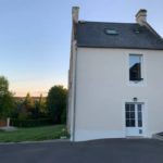 Maison blanche à Feuguerolles-Bully, entourée de verdure et située dans un cadre rural.