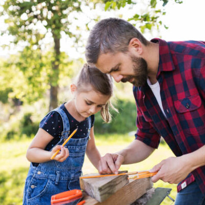 Un adulte et un enfant travaillent ensemble sur un projet de bricolage en plein air.