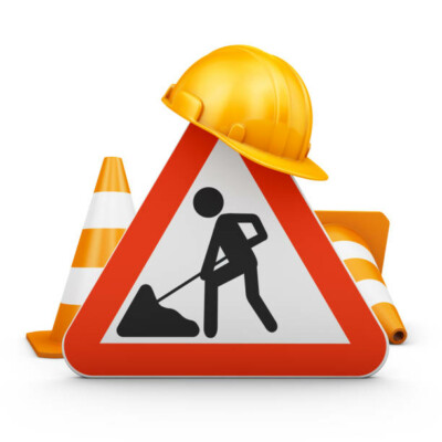 Panneau de chantier avec un homme en train de travailler, un casque de sécurité et des cônes de signalisation.