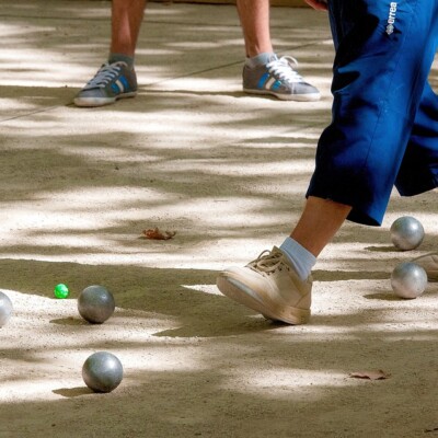 Jeux de pétanque sur une terre battue, avec des joueurs positionnés autour des boules.