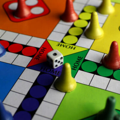 Un plateau de jeu de société avec des pions colorés et un dé, représentant un moment ludique en famille ou entre amis.