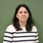 IMG_2545b Portrait d'une femme avec un pull rayé, devant un mur vert.