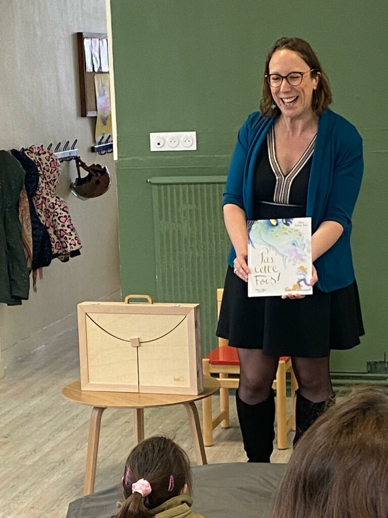 Animation de lecture pour enfants, avec une intervenante présentant un livre, dans un cadre éducatif convivial.