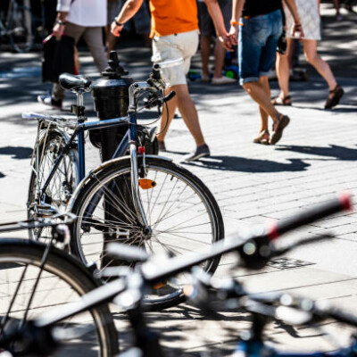 Vélos stationnés sur un trottoir animé, avec des piétons en arrière-plan à Feuguerolles-Bully.