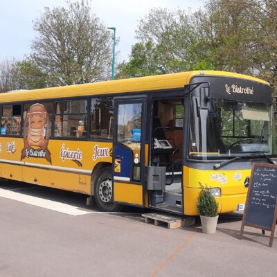 Un bus jaune servant de café et épicerie, stationné dans un village rural à Feuguerolles-Bully.
